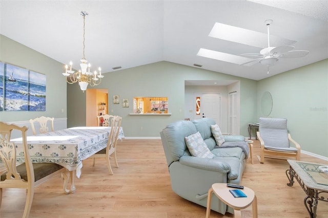 living room featuring light hardwood / wood-style flooring, ceiling fan with notable chandelier, and vaulted ceiling with skylight