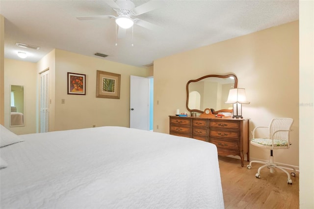 bedroom with a textured ceiling, a closet, light hardwood / wood-style flooring, and ceiling fan