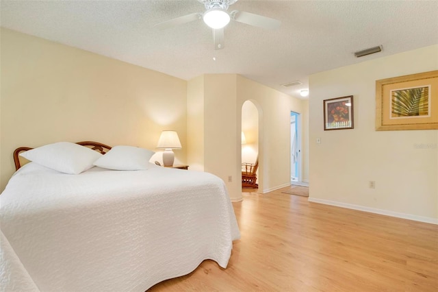 bedroom with ceiling fan, light wood-type flooring, and a textured ceiling