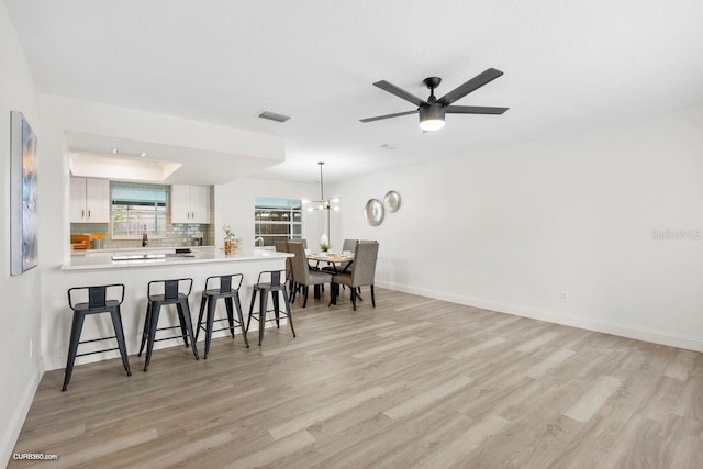 dining space featuring ceiling fan with notable chandelier and light wood-type flooring