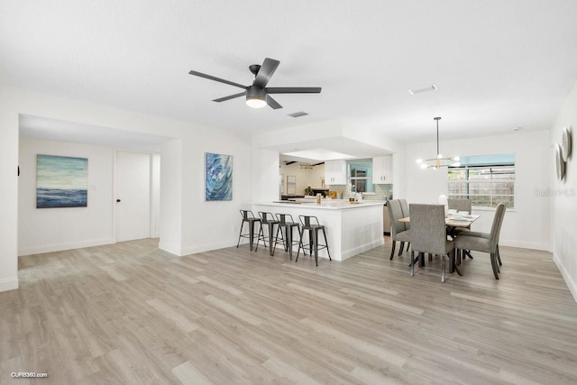 dining space with light hardwood / wood-style floors and ceiling fan with notable chandelier