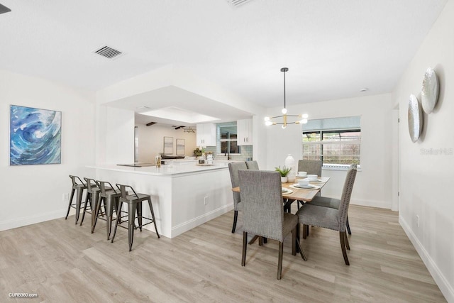 dining space featuring a notable chandelier and light wood-type flooring