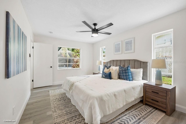 bedroom featuring a textured ceiling, light hardwood / wood-style floors, and ceiling fan