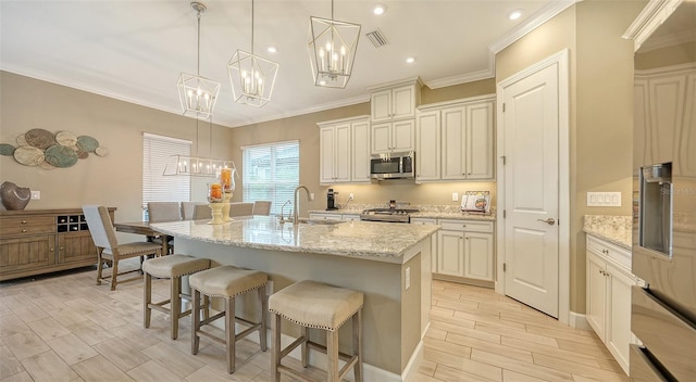 kitchen featuring light stone counters, a kitchen island with sink, sink, range, and hanging light fixtures