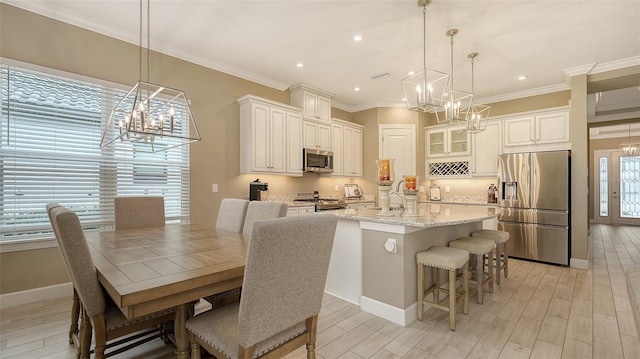 kitchen featuring white cabinets, a kitchen breakfast bar, stainless steel appliances, and an island with sink