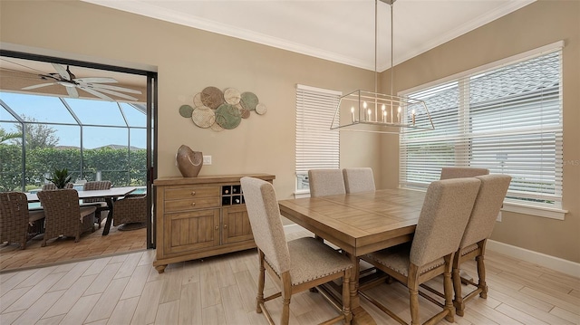 dining space with light wood finished floors, ceiling fan with notable chandelier, baseboards, and ornamental molding