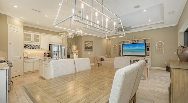 dining room with ceiling fan, ornamental molding, sink, and a tray ceiling