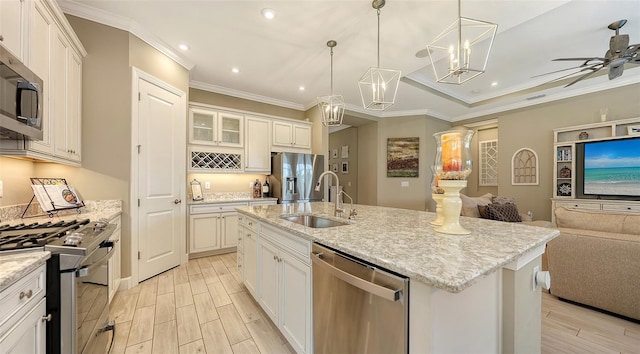 kitchen with a kitchen island with sink, white cabinetry, sink, and appliances with stainless steel finishes