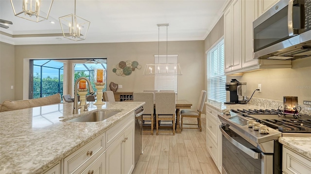 kitchen with light stone counters, sink, hanging light fixtures, and appliances with stainless steel finishes