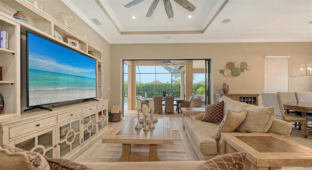 living room featuring light hardwood / wood-style flooring, a raised ceiling, and ceiling fan