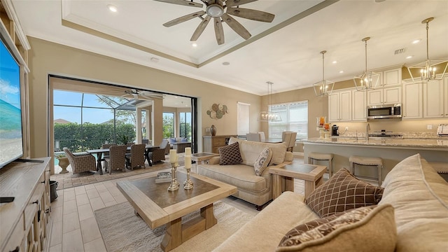 living room with ceiling fan, a healthy amount of sunlight, and a tray ceiling