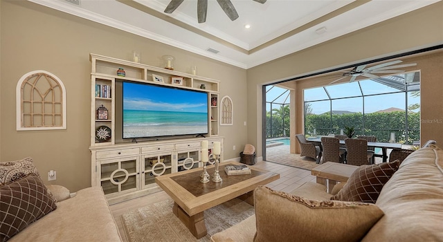 living room with ceiling fan, a raised ceiling, and ornamental molding