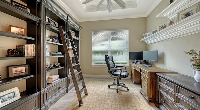 office space featuring crown molding, baseboards, light wood-type flooring, a raised ceiling, and a ceiling fan