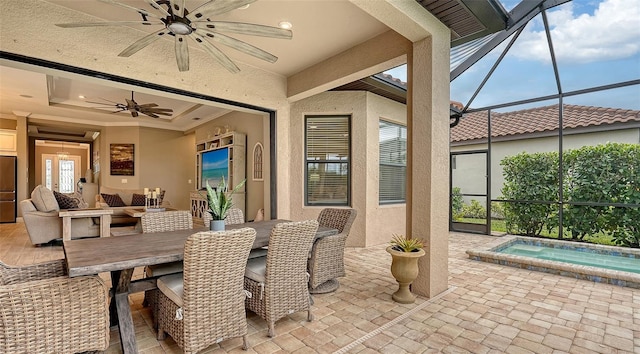 view of patio with a lanai, outdoor dining space, ceiling fan, and an outdoor hot tub