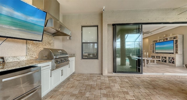 kitchen featuring light stone counters, fridge, wall chimney exhaust hood, white cabinets, and brick floor