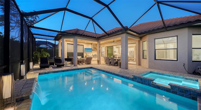 pool at dusk featuring ceiling fan, a lanai, pool water feature, an in ground hot tub, and a patio