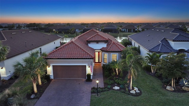 view of front of property with stucco siding, a garage, a tile roof, decorative driveway, and a residential view