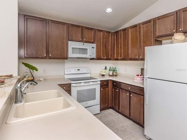 kitchen featuring a textured ceiling, white appliances, sink, light tile patterned floors, and lofted ceiling