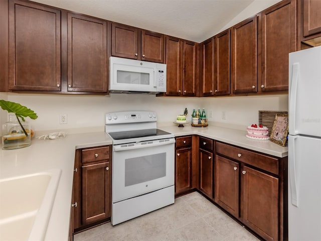 kitchen featuring white appliances, sink, light tile patterned floors, a textured ceiling, and dark brown cabinetry