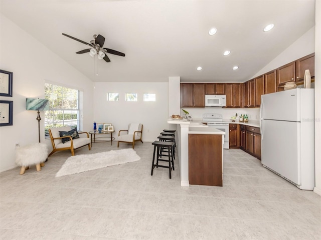 kitchen with a center island, a kitchen breakfast bar, vaulted ceiling, white appliances, and light tile patterned floors