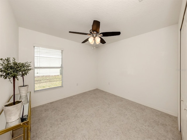 unfurnished room featuring a textured ceiling, ceiling fan, and light carpet