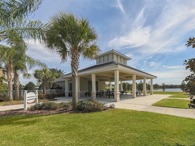 surrounding community with a water view and a lawn