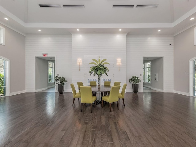 dining space featuring dark hardwood / wood-style flooring, crown molding, and a high ceiling