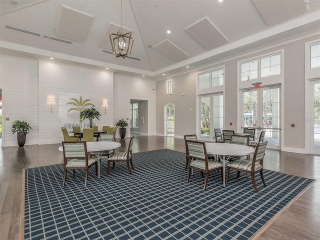 dining area with hardwood / wood-style floors, a towering ceiling, french doors, and a chandelier