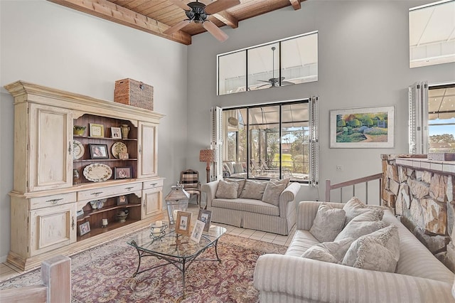 living room featuring wood ceiling, beam ceiling, a high ceiling, and a ceiling fan