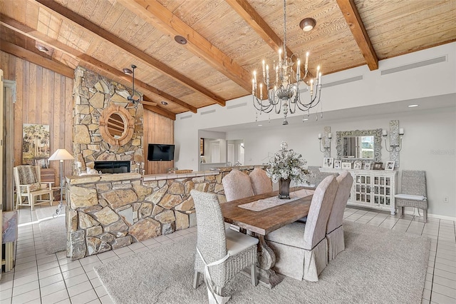 dining room featuring wood ceiling, beamed ceiling, a stone fireplace, and light tile patterned floors