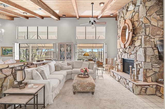 living room featuring beam ceiling, a fireplace, a high ceiling, a ceiling fan, and wood ceiling