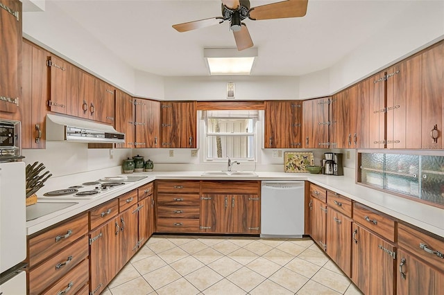 kitchen featuring brown cabinetry, white appliances, a sink, and under cabinet range hood