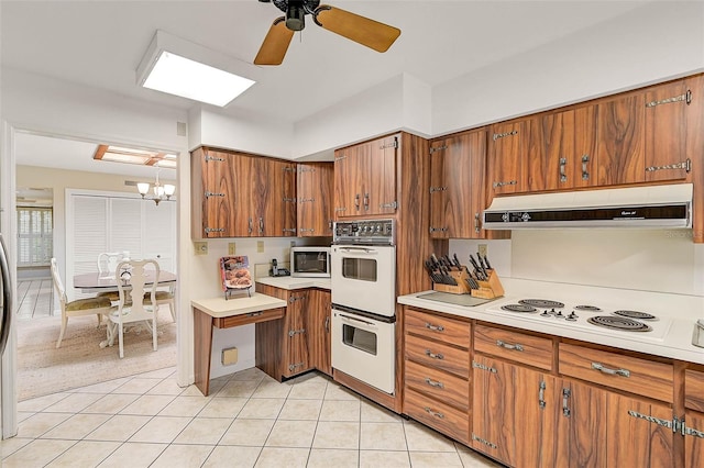 kitchen with brown cabinetry, white appliances, light countertops, and under cabinet range hood