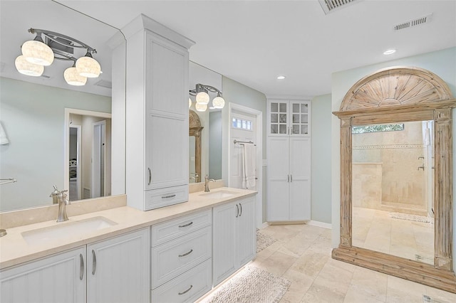 bathroom with a sink, visible vents, and a shower stall