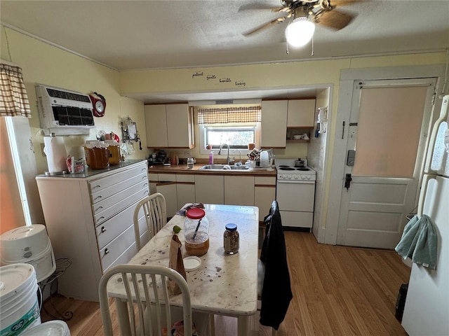 kitchen with white appliances, sink, ceiling fan, light hardwood / wood-style floors, and a wall unit AC