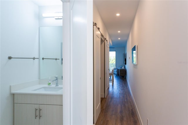 corridor featuring a barn door, sink, and dark wood-type flooring