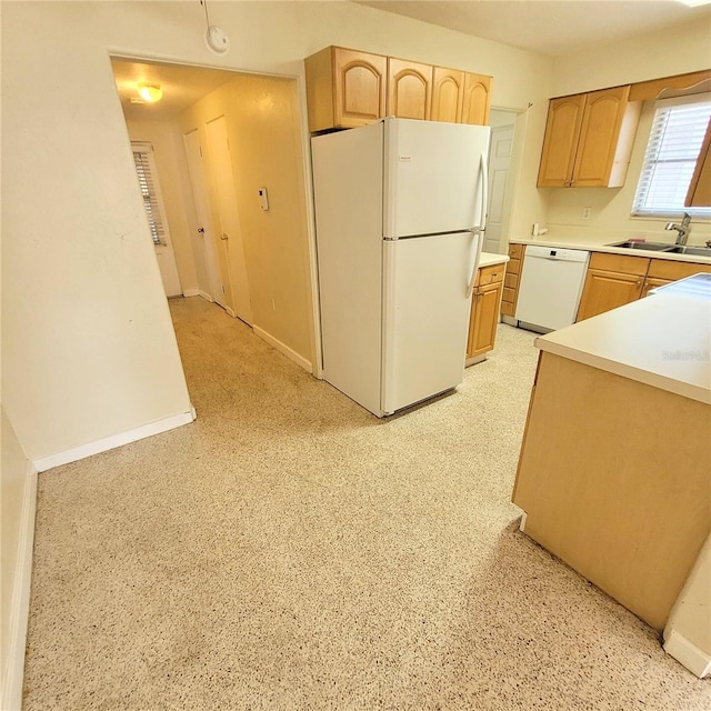 kitchen with white appliances, sink, and light brown cabinetry