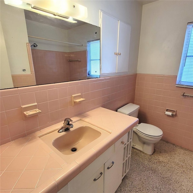 bathroom with vanity, tile walls, and toilet