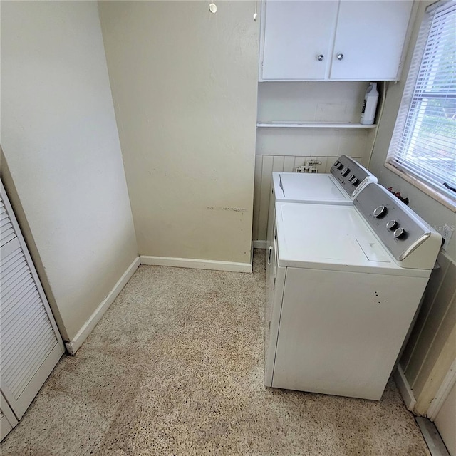 clothes washing area featuring washer and clothes dryer and cabinets