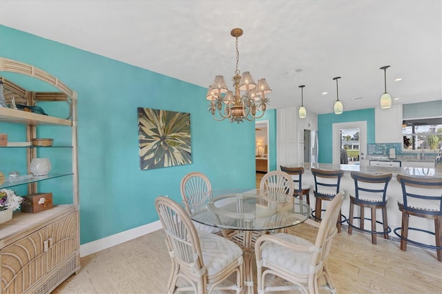 dining space with light hardwood / wood-style floors, an inviting chandelier, and sink