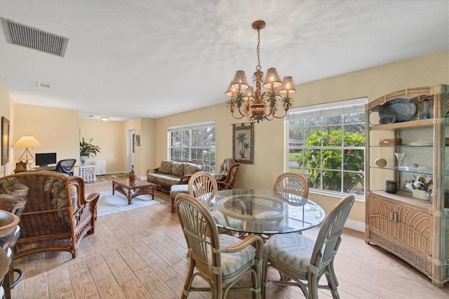 dining area featuring a wealth of natural light, an inviting chandelier, and light wood-type flooring