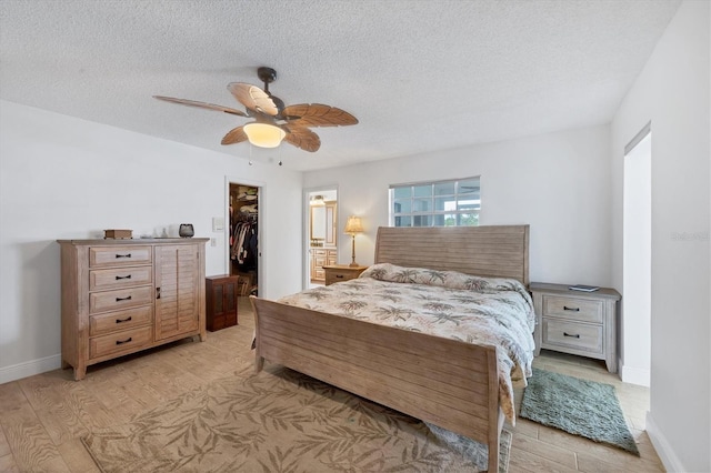 bedroom featuring a walk in closet, ceiling fan, a closet, and a textured ceiling