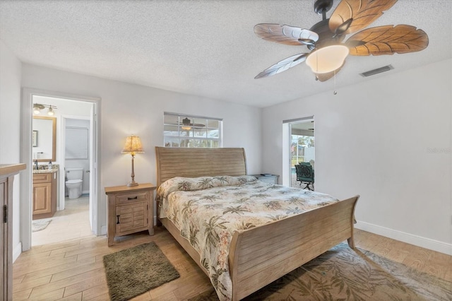 bedroom featuring a textured ceiling, light wood-type flooring, ensuite bath, and ceiling fan