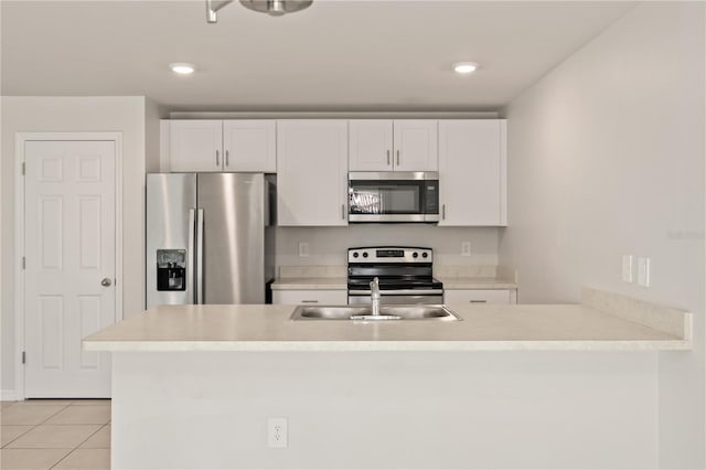 kitchen with sink, light tile patterned floors, kitchen peninsula, white cabinets, and appliances with stainless steel finishes