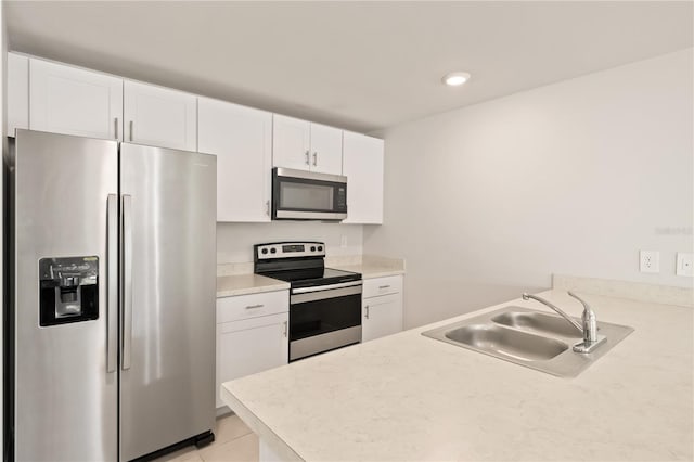 kitchen with white cabinets, appliances with stainless steel finishes, light tile patterned flooring, and sink