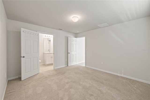 unfurnished bedroom featuring connected bathroom and light carpet