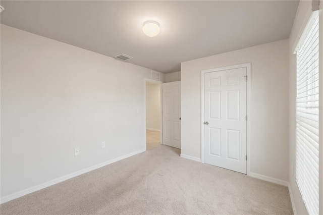 unfurnished bedroom featuring light carpet and a closet