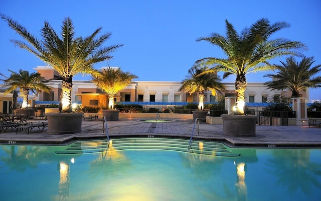 pool at dusk featuring a patio