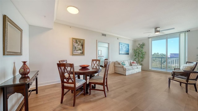 dining area featuring light hardwood / wood-style flooring, ornamental molding, ceiling fan, and a wall of windows