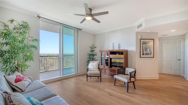 living area with baseboards, visible vents, light wood-style flooring, ceiling fan, and ornamental molding